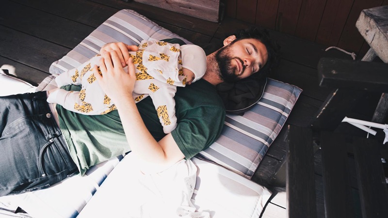 Mand sover med baby på sin mave