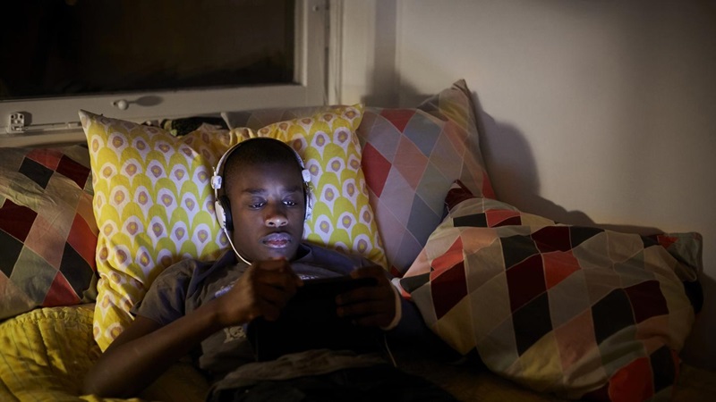 Mand kigger på sin tablet mens han ligger i sengen