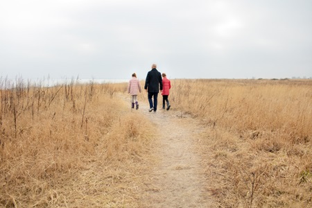 En far går med sine to børn ude ved vandet. Med en livsforsikring er din familie økonomisk dækket, hvis du pludselig dør.