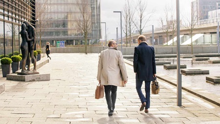 To mænd går udenfor blandt konktorbygninger